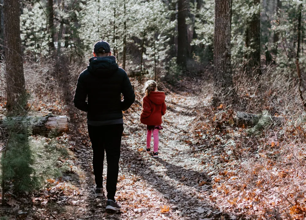 Adult and child hiking a trail in the woods