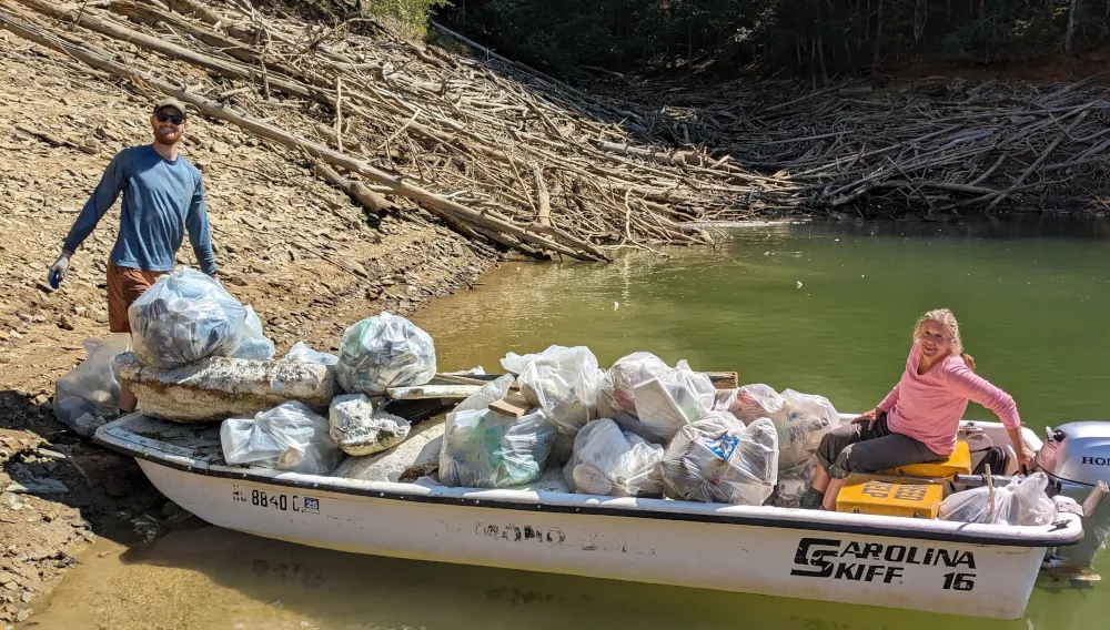 photo of 2 people in a boat filled with trash bags